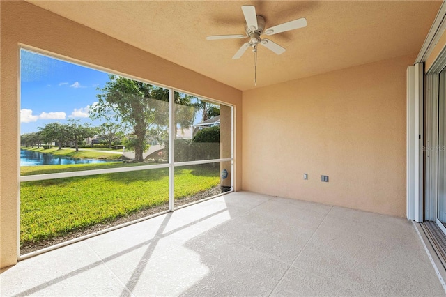 unfurnished sunroom featuring ceiling fan and a water view