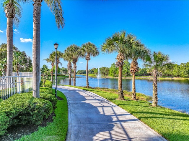 surrounding community with a water view and a yard