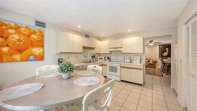 kitchen featuring sink, light tile patterned floors, a textured ceiling, and white appliances