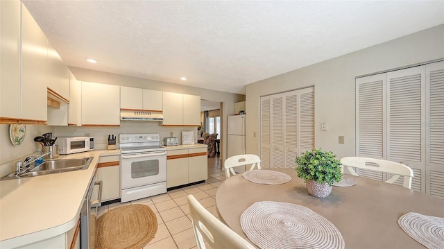 kitchen featuring sink, light tile patterned floors, a textured ceiling, and white appliances