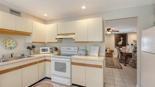 kitchen with sink, white appliances, light tile patterned floors, ceiling fan, and white cabinets