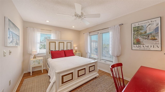 bedroom with wood-type flooring, multiple windows, and a textured ceiling