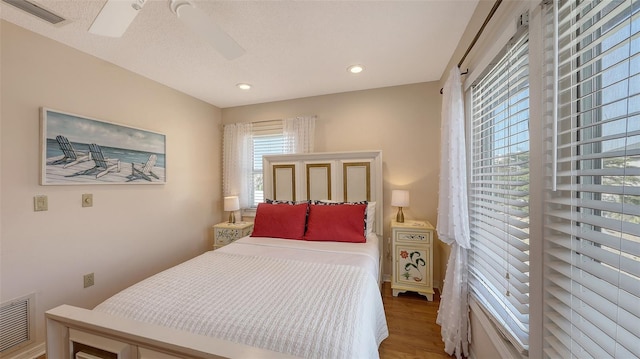 bedroom with wood-type flooring, a textured ceiling, and ceiling fan