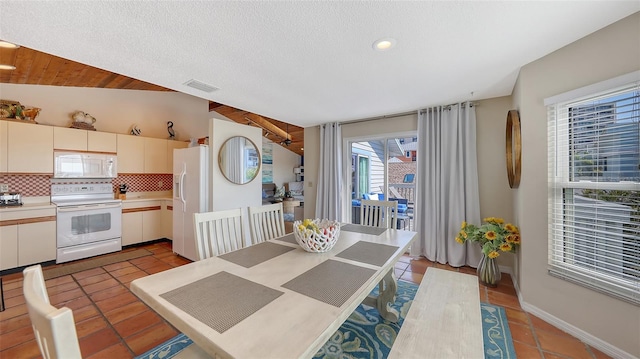 tiled dining area with lofted ceiling and a textured ceiling