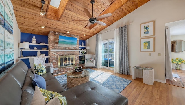 living room featuring a fireplace, a skylight, ceiling fan, light hardwood / wood-style floors, and wooden ceiling