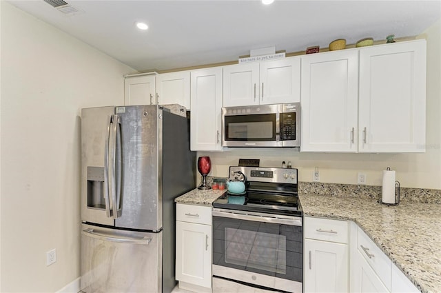 kitchen featuring stainless steel appliances, light stone countertops, and white cabinets