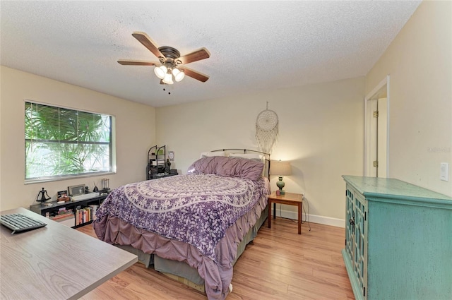 bedroom featuring ceiling fan, light hardwood / wood-style flooring, and a textured ceiling