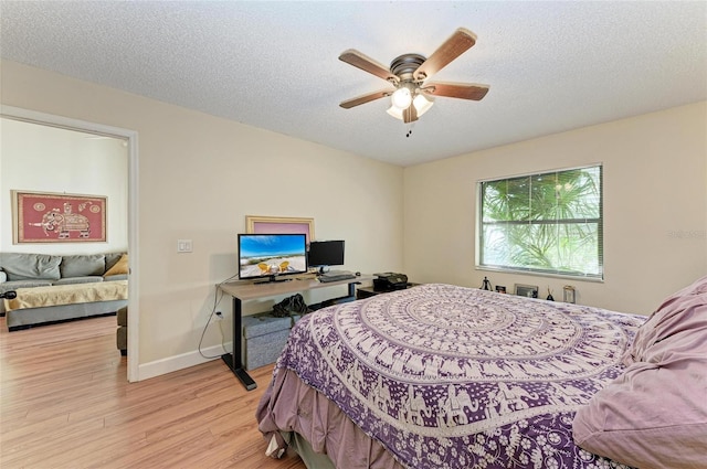 bedroom featuring ceiling fan, light hardwood / wood-style flooring, and a textured ceiling