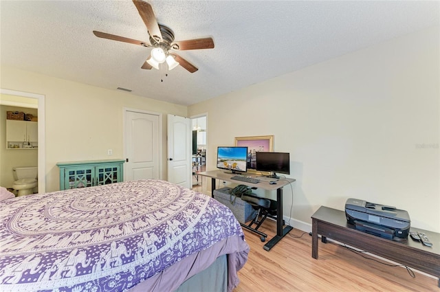 bedroom with ceiling fan, ensuite bath, light hardwood / wood-style floors, and a textured ceiling