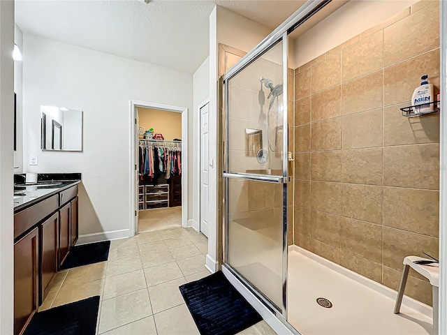 bathroom featuring walk in shower, vanity, tile patterned flooring, and a textured ceiling