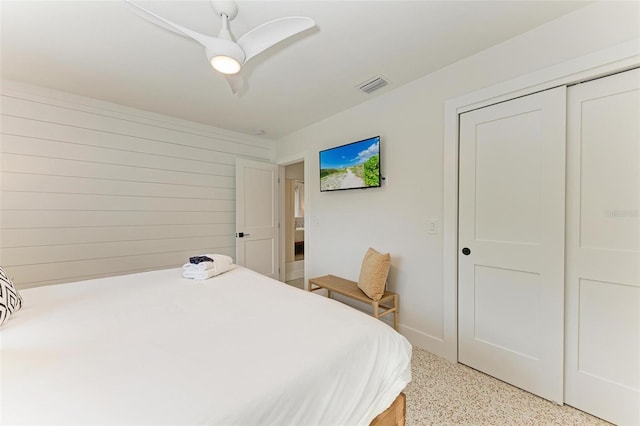 bedroom with wooden walls, a closet, and ceiling fan