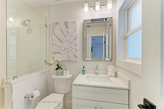 bathroom with vanity, a tile shower, and toilet