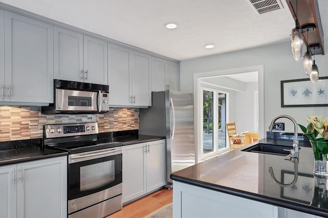 kitchen featuring sink, gray cabinetry, tasteful backsplash, appliances with stainless steel finishes, and light hardwood / wood-style floors