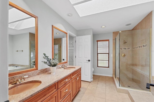 full bath featuring double vanity, a stall shower, a skylight, and a sink