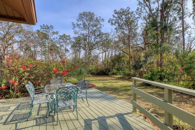 wooden terrace with outdoor dining area and a yard