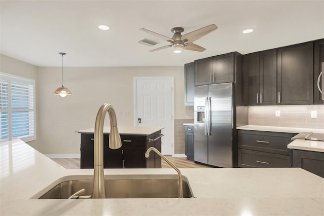 kitchen with decorative light fixtures, tasteful backsplash, sink, stainless steel fridge, and dark brown cabinetry