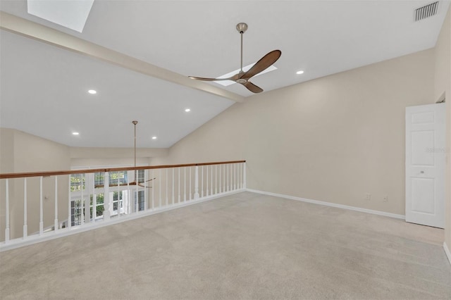 carpeted empty room featuring vaulted ceiling with skylight and ceiling fan