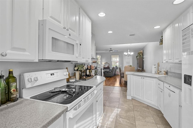 kitchen featuring a sink, white appliances, ceiling fan with notable chandelier, and white cabinetry