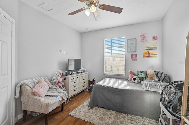 bedroom featuring visible vents, a textured ceiling, a ceiling fan, and wood finished floors