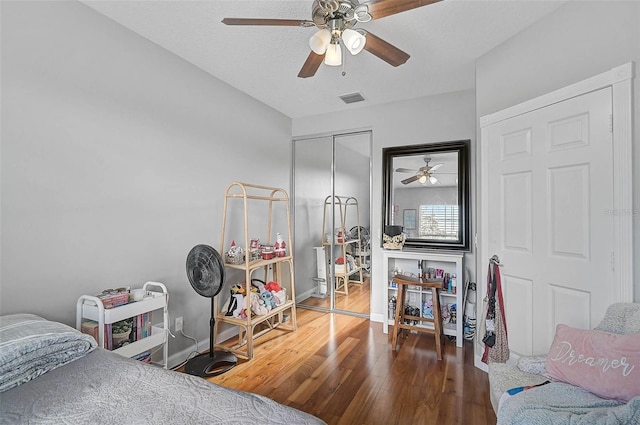 bedroom with visible vents, baseboards, wood finished floors, a closet, and a ceiling fan