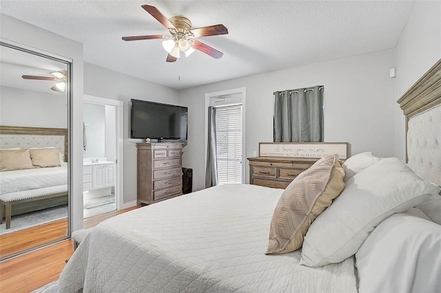 bedroom with ceiling fan, a textured ceiling, ensuite bath, and wood finished floors