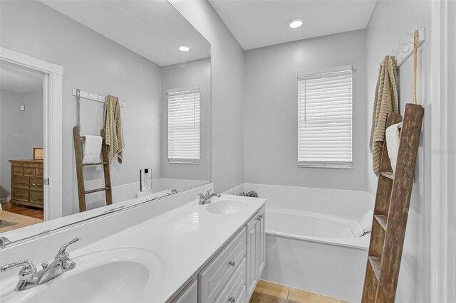 full bath with a bath, recessed lighting, double vanity, and a sink