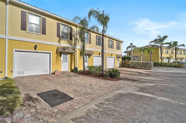 view of property with an attached garage, driveway, and stucco siding