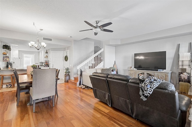 living area featuring visible vents, ceiling fan with notable chandelier, stairs, and light wood finished floors