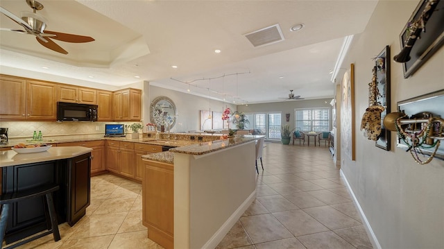 kitchen featuring visible vents, backsplash, light tile patterned flooring, black microwave, and a peninsula