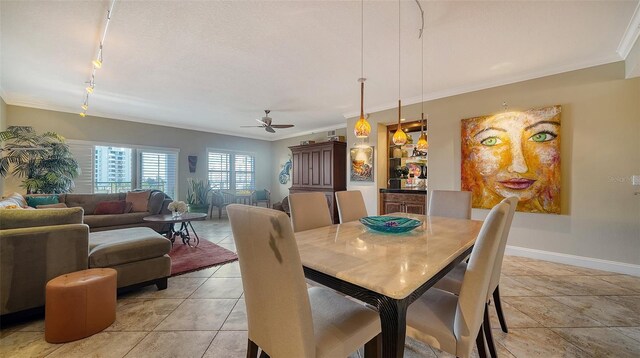 dining room with baseboards, light tile patterned flooring, rail lighting, and crown molding