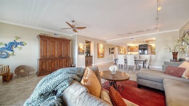 living area featuring light tile patterned floors, visible vents, baseboards, a ceiling fan, and ornamental molding