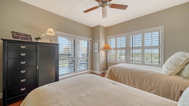 bedroom with ceiling fan, multiple windows, wood finished floors, and baseboards