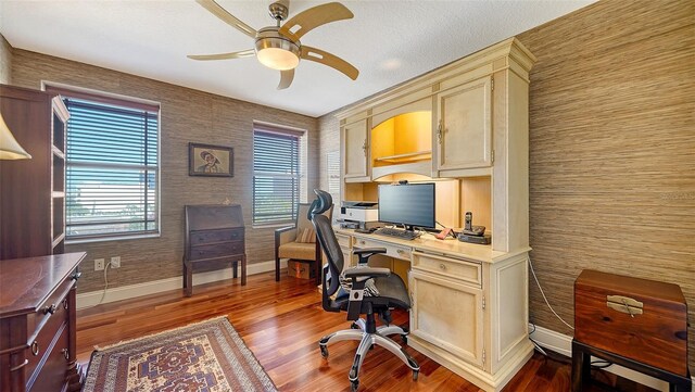 office featuring baseboards, a ceiling fan, and dark wood-style flooring