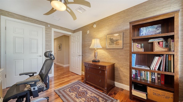 office area with baseboards, wood finished floors, visible vents, and a ceiling fan