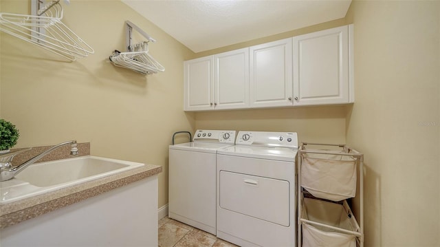 washroom featuring a sink, cabinet space, baseboards, and washer and dryer