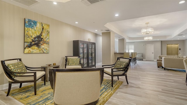 sitting room with a tray ceiling, recessed lighting, visible vents, light wood-style flooring, and baseboards