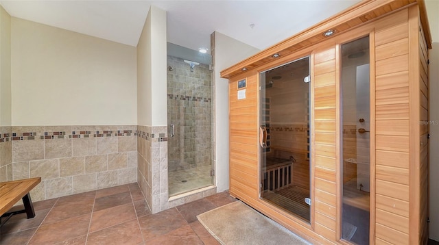 full bathroom with tile walls, a wainscoted wall, and a shower stall