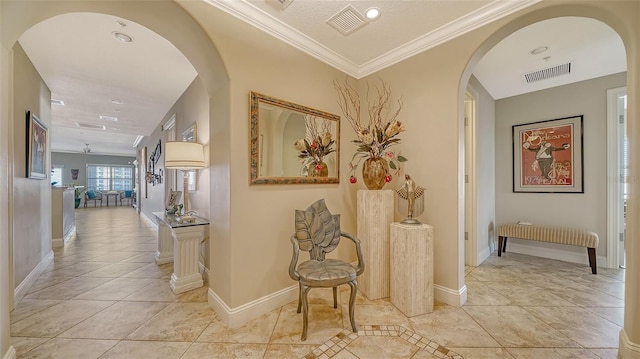 hall with baseboards, visible vents, arched walkways, and crown molding