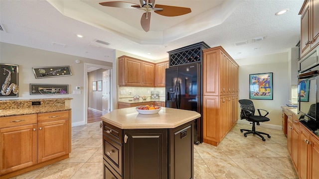 kitchen featuring decorative backsplash, a center island, oven, a tray ceiling, and black fridge