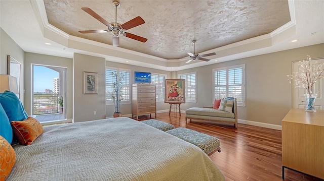 bedroom with a raised ceiling, baseboards, and wood finished floors