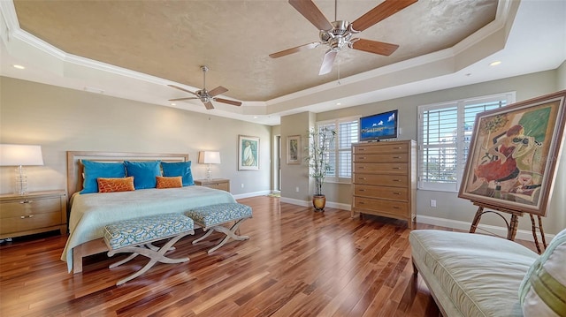 bedroom featuring hardwood / wood-style flooring, recessed lighting, baseboards, a tray ceiling, and crown molding