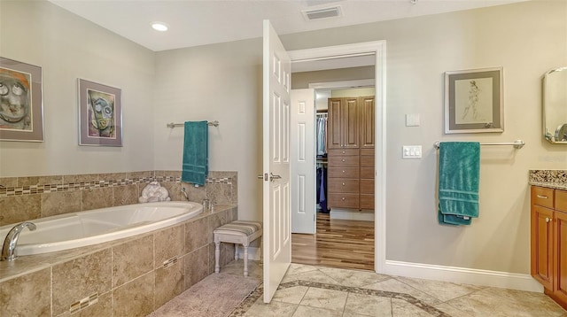 full bathroom with visible vents, vanity, baseboards, and a bath