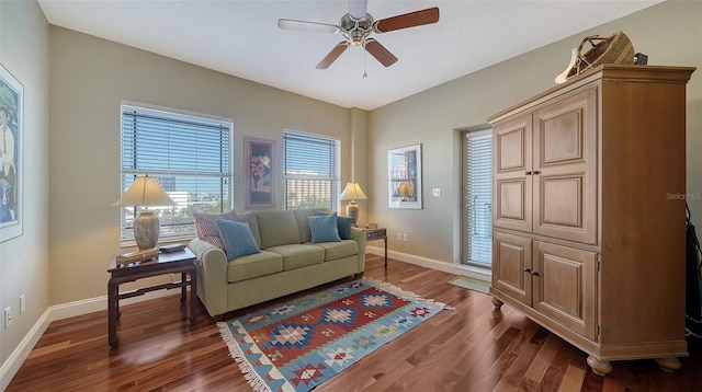 living room featuring dark wood-style floors, ceiling fan, and baseboards