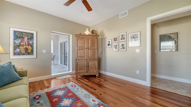 sitting room with ceiling fan, lofted ceiling, visible vents, baseboards, and light wood-style floors