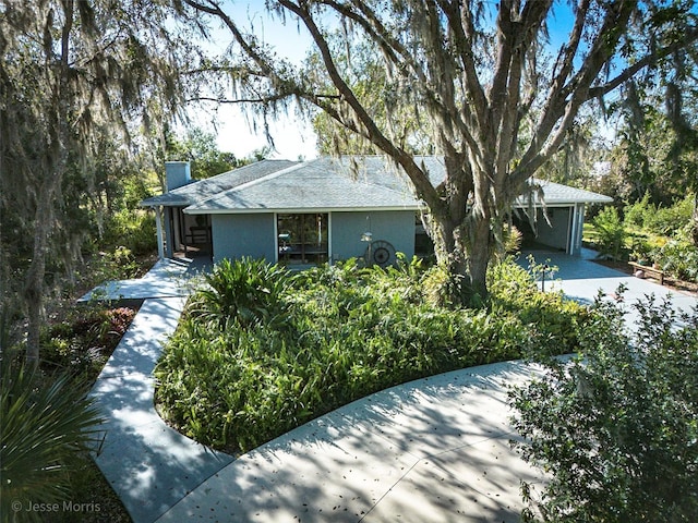 single story home with a chimney and stucco siding