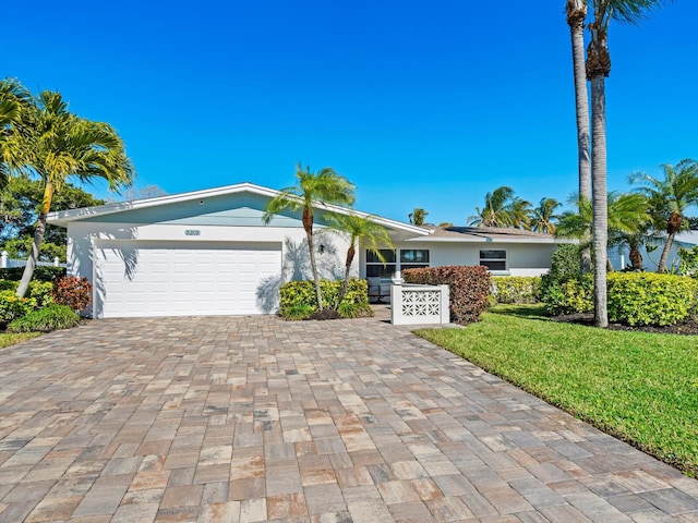 view of front of property featuring a garage, a front yard, decorative driveway, and stucco siding