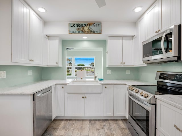 kitchen with appliances with stainless steel finishes, white cabinetry, and a sink