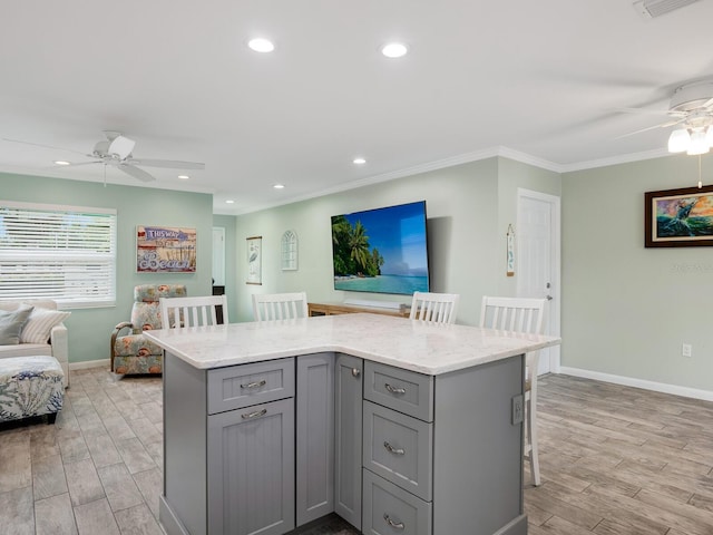 kitchen featuring light wood finished floors, a kitchen island, a breakfast bar, open floor plan, and gray cabinetry