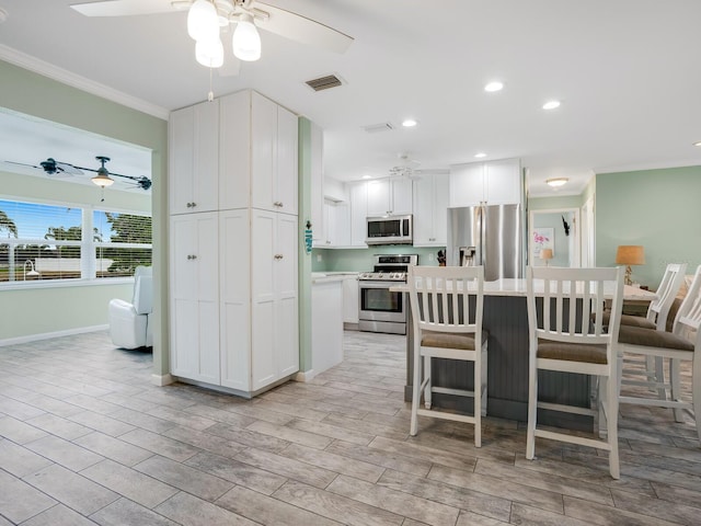 kitchen with stainless steel appliances, light countertops, a ceiling fan, and white cabinets