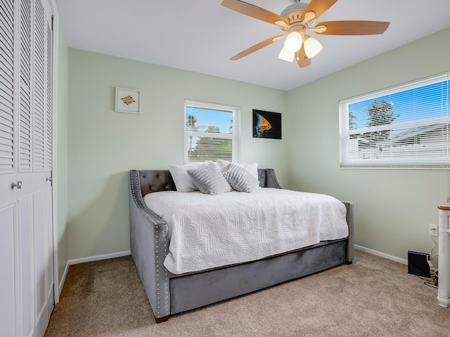 carpeted bedroom with ceiling fan and a closet